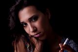 Young sexy brunette with cigarette. Isolated on black