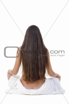 nude woman with long hair sitting on the floor - view from behind