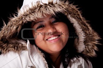 Portrait of a young latin woman with a furry hood , in autumn/winter clothes, isolated on black. Studio shot