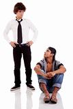 two men of different ethnicity, one sitting looking at the other standing, isolated on white, studio shot