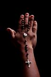 hands of a young latin men with a crucifix, isolated on black, studio shot