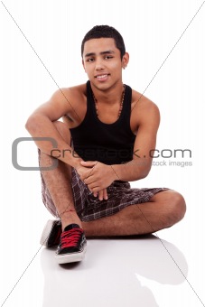 young and handsome latin man, seated on floor isolated on white background, studio shot
