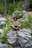 Girl sitting on a rock with laptop, looking excited