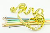 Colorful knitting needles and a yellow measuring tape