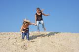 two girls jumping on a sand-pit