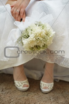 Bouquet of bride against dress and shoes
