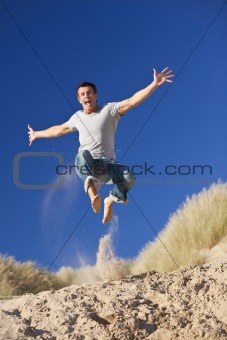 Happy Excited Young Man Jumping On A Beach