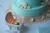 Beach themed wedding cake with lit candle
