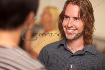 Smiling Young Man with Glass of Wine Socializing in a Party Setting.