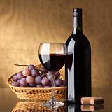A bottle of red wine, glass and grapes