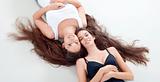 two sisters with very long brown hair lying on the floor, looking up