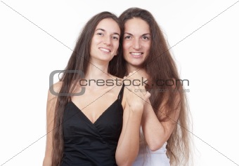 two sisters with very long brown hair standing smiling - isolated on white