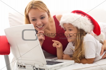 Woman and little girl playing on a laptop at christmas time