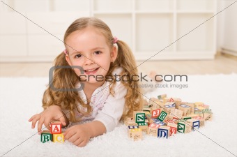 Little girl with alphabet wooden blocks playing