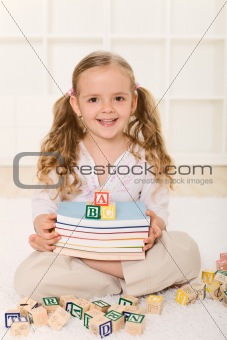Little girl with books and alphabet wooden blocks