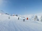 Skiers on wide ski slope on sunny day