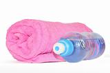Twisted pink towel and bottle of sparkling water isolated on whi