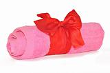 Twisted pink towel with red ribbon bow isolated on white