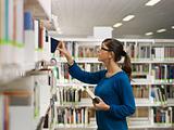 girl choosing book in library