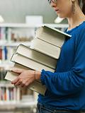 woman holding pile of books in library