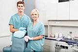 Confident male and female dentists smiling at dental clinic