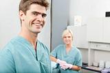 Male dentist with female assistant standing at dental clinic