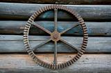 Machinery wheel on log wall