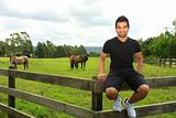 man sitting on th efence of a horse paddock