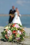 Bouquet, bride and groom. Focus on the bouquet.