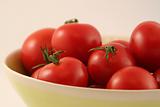 Several red tomatoes in agreen bowl