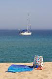 beach towel and bag with yacht in background, corsica, france