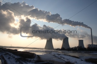 View of coal power plant against sun and huge fumes