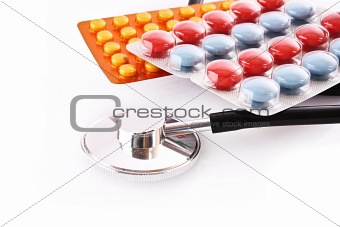 Tablets and stethoscope isolated on white