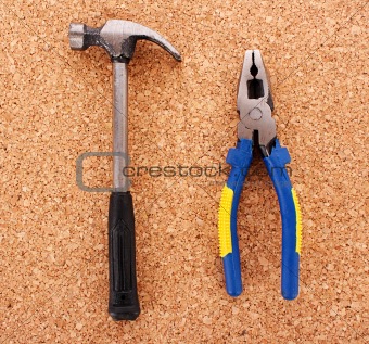 Hammer and pliers on cork board surface