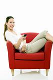 Young woman sitting on a chair with remote control on white background studio