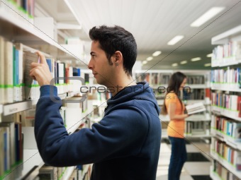 guy taking book from shelf in library