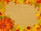 Fall leaves and pumpkins on wood background.
