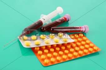 Medical test tubes with blood and medicines on green