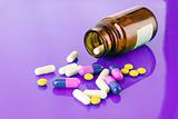 Pill bottle with coloured pills on puple