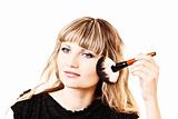 beautiful young woman applying makeup with brush
