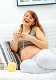 Laughing beautiful  pregnant woman knitting  for her baby.
