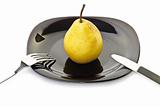 Yellow pear on a black plate with fork and knife
