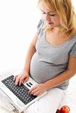Beautiful pregnant woman sitting on the floor with laptop