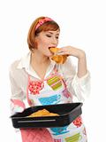 Beautiful cooking woman in apron eating fresh made croissant 