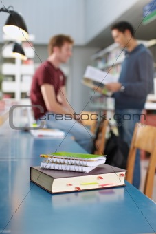 book and notepads on desk in library