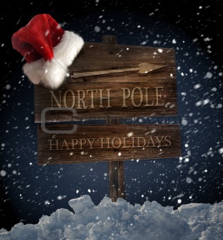 Wooden sign with santa hat on snowy background