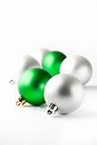 Green and silver Christmas baubles on white