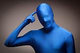 Man Wearing Full Blue Nylon Bodysuit Scratching His Head on a Grey Background.
