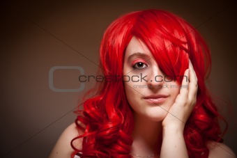 Portrait of an Attractive Red Haired Woman with Her Hand on Her Face on a Grey Background.