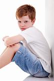 cute boy, sitting on the floor tired, isolated on white, studio shot